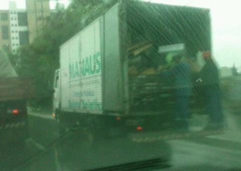 Funcionário vai pendurado na chuva em caminhão da Prefeitura de Manaus