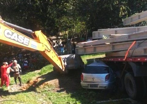 Carreta tomba sobre veículo e homem fica preso nas ferragens