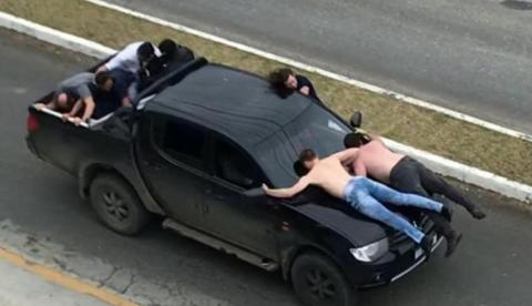 Ladrões fogem da polícia com reféns em capô de caminhonete