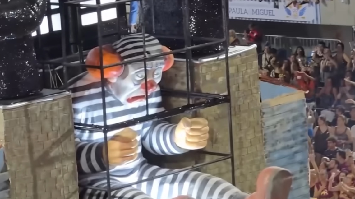 Um dos carros aleg&oacute;ricos trouxe uma representa&ccedil;&atilde;o provocativa de Bolsonaro como um palha&ccedil;o detido, utilizando uma tornozeleira eletr&ocirc;nica danificada.