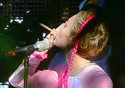 Miley Cyrus usa camiseta com seios desenhados e fuma cigarro suspeito