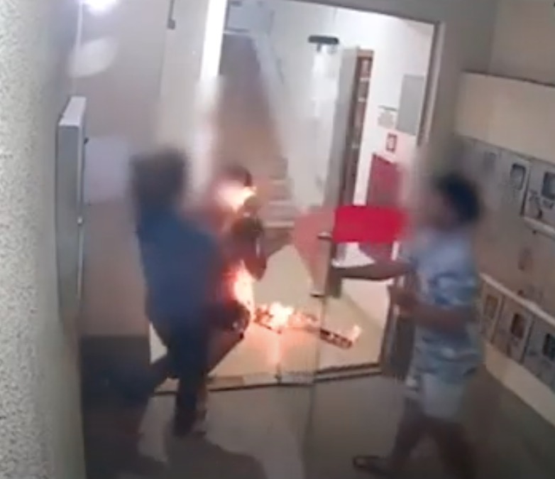 Mulher surge pegando fogo na porta de prédio em cena chocante; confira