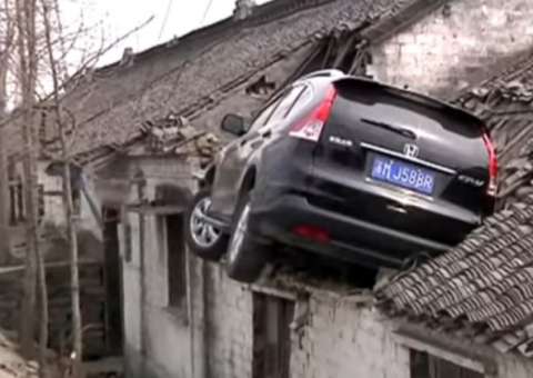 Motorista tenta desviar de acidente e carro vai parar em telhado de casa