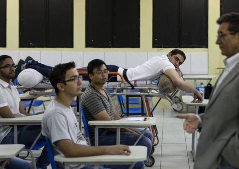 Com bala alojada na coluna, aluno assiste às aulas em uma maca