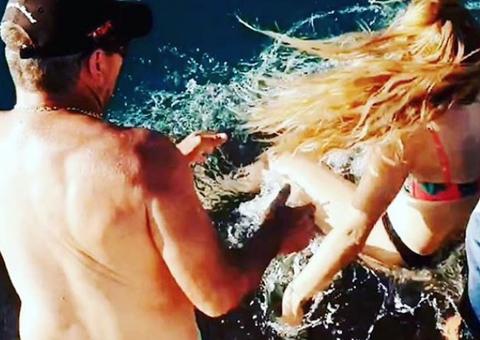   Mulher tenta alimentar tubarão e acaba puxada e abocanhada pelo animal