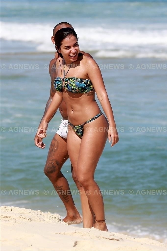 De barriga para cima, Anitta é flagrada fazendo topless em praia do Rio de Janeiro