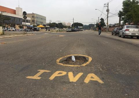 Buracos em vias de cidade são pintados com as siglas 'IPVA' e 'IPTU'