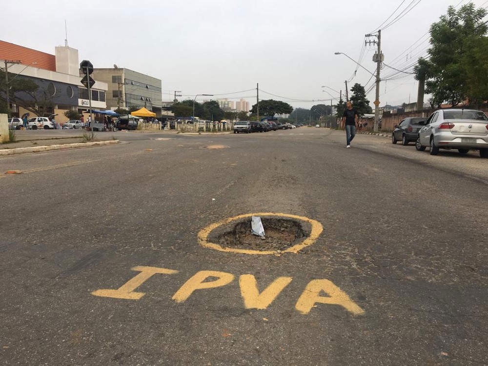 Buracos em vias de cidade são pintados com as siglas 'IPVA' e 'IPTU'
