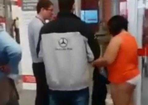 Mulher se aborrece com alarme de porta de banco e tira a roupa