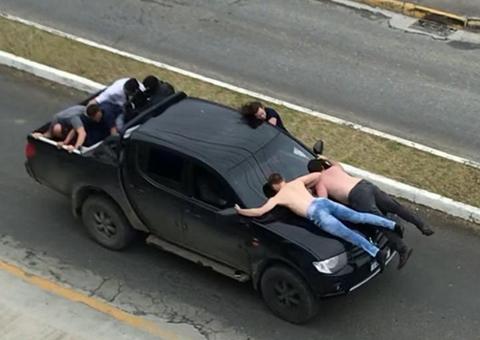 Ladrões fogem da polícia com reféns em capô de caminhonete