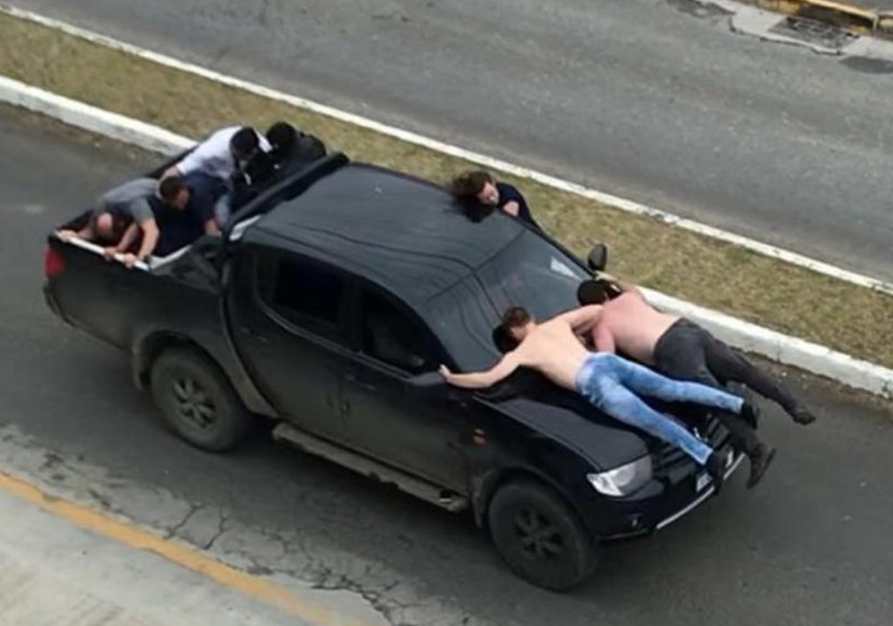 Ladrões fogem da polícia com reféns em capô de caminhonete