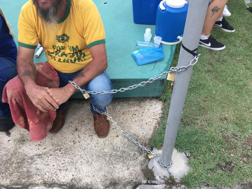 Acorrentado a poste em frente a Aleam, caminhoneiro pede redução de ICMS sobre combustíveis