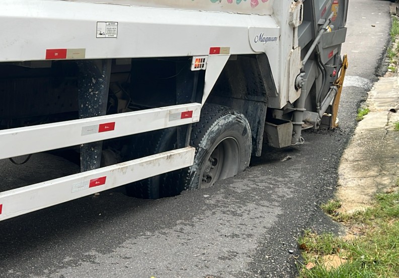 Caminhão de lixo fica preso após cratera engolir roda no Coroado