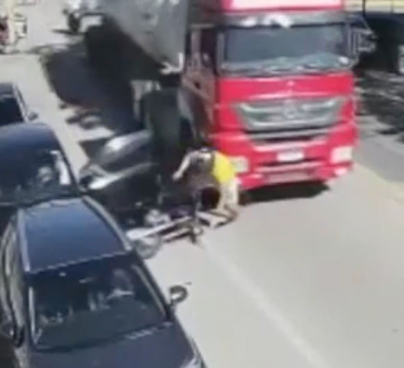Motociclista vai parar embaixo de caminhão após ser atingido por porta de carro