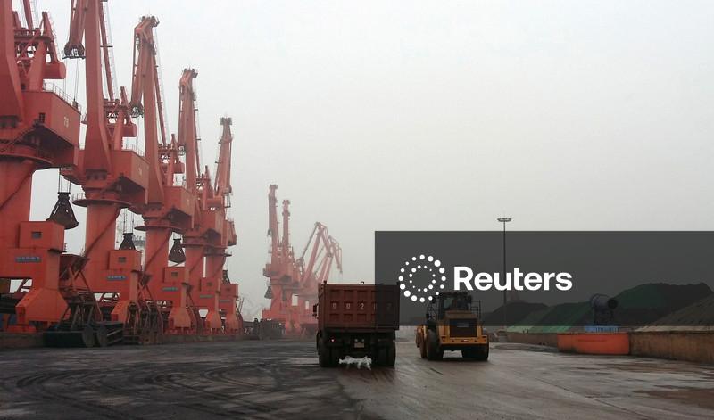 Caminhões circulam dentro de um depósito de minério de ferro no Terminal Huanggang do Porto de Qingdao, em Qingdao, província de Shandong