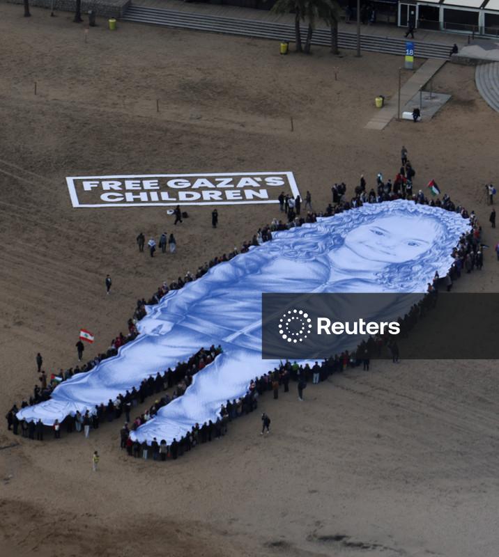Retrato gigante de menina morta na guerra de Gaza é estendido em praia de Barcelona