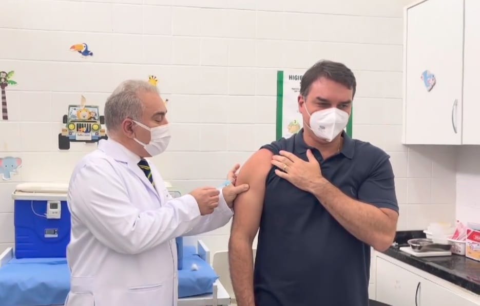 Vídeo: Flávio Bolsonaro é chamado de miliciano ao se vacinar e faz gesto obsceno