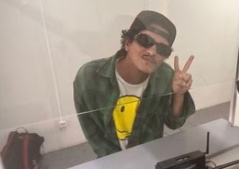 Bruno Mars chega ao Brasil e posa com fã em aeroporto