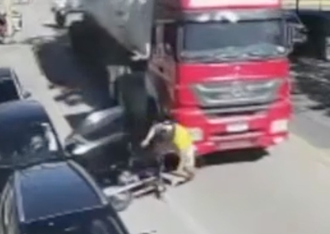 Motociclista vai parar embaixo de caminhão após ser atingido por porta de carro