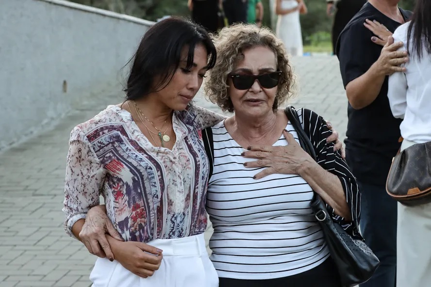 Danni Suzuki consola mãe de Rico Tavares em velório do maquiador