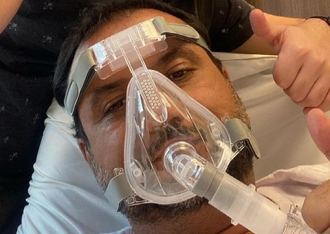 Geraldo Luís caminha com cilindro de oxigênio em corredor de UTI