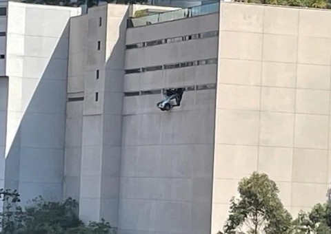 Carro de luxo fica pendurado a metros de altura ao bater em parede de prédio; vídeo