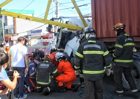 Motorista fica preso às ferragens após carreta destruir limitador de altura em avenida