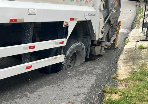 Caminhão de lixo fica preso após cratera engolir roda no Coroado