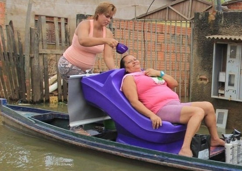 Cabeleireira improvisa e atende clientes em canoa durante cheia no Acre